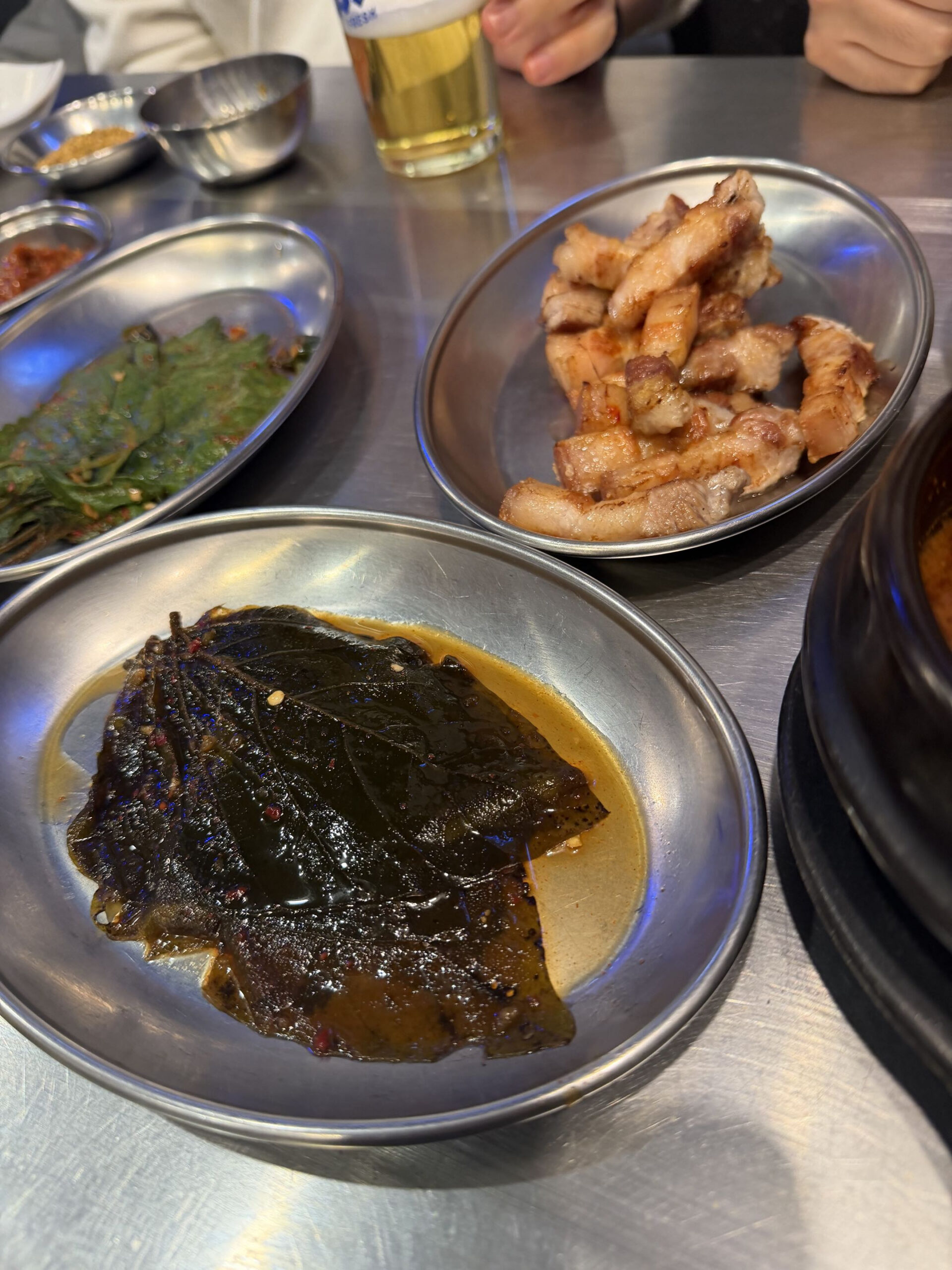Table spread: soybean leaves, pickles, grilled meat